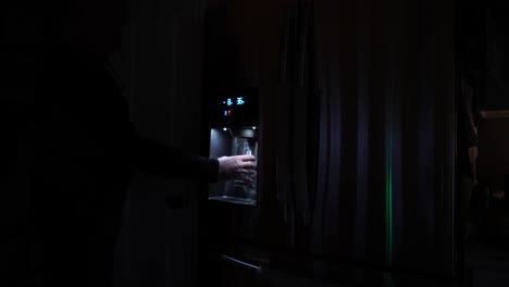 Man's-hand-seen-getting-a-glass-of-drinking-water-from-the-refrigerator-door-dispenser