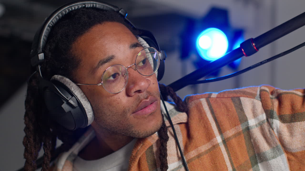 primer plano de un grabador de sonido de película masculino con auriculares sosteniendo un micrófono disparando una película o video en el estudio