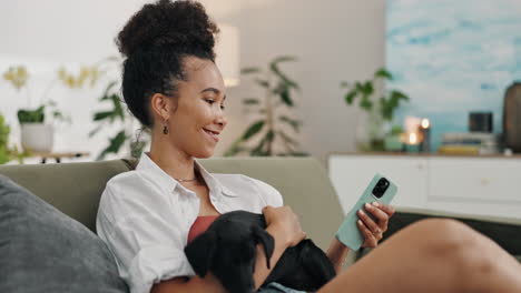 woman relaxing on couch with puppy and smartphone