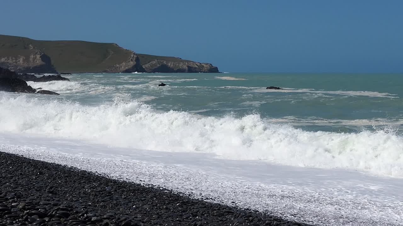 las olas chocan contra la playa pedregosa en un claro día de verano - playa plana de pájaros
