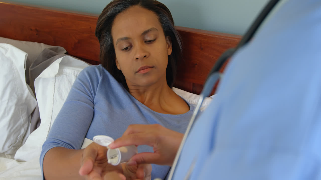 Female doctor giving medicine to mature woman at home 4k
