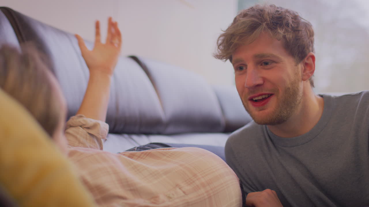 사랑하는 커플과 남자가 임신한 파트너의 배를 듣고 집에서 의수 팔을 가지고 있습니다.