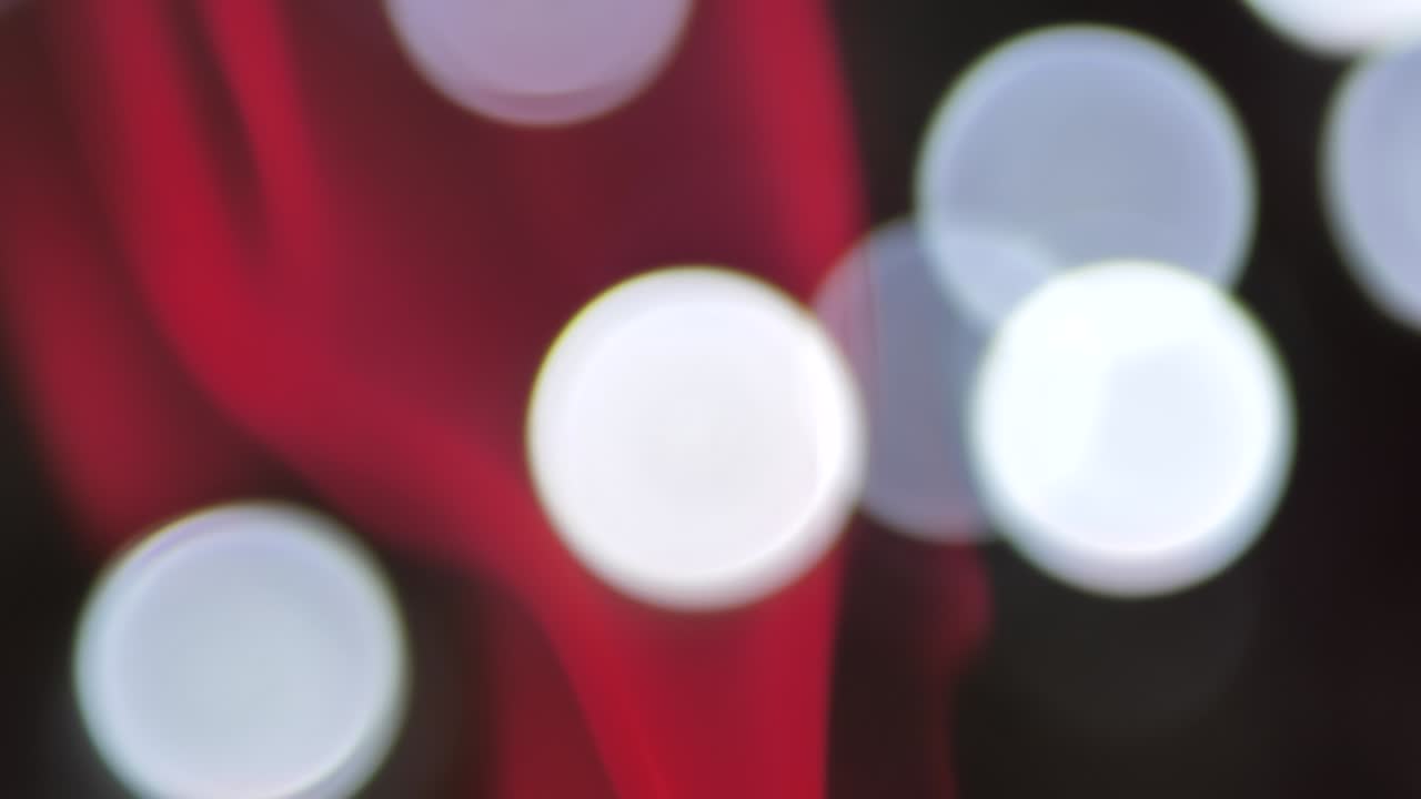 Red smoke moves up slowly, round lights move in the background, smoke and lights are blurred