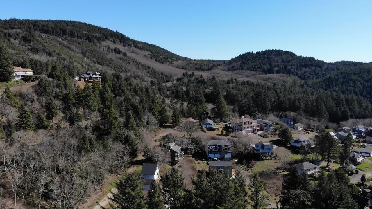 drone vuela sobre casas en las montañas y pinos por la tarde