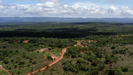 Schöne-Absteigende-Luftdrohnenaufnahme-Der-Brasilianischen-Landschaft-Mit-Einer-Kleinen-Roten-Unbefestigten-Straße-Im-Chapada-Diamantina-Nationalpark-Im-Norden-Brasiliens-Und-Einem-Sonnigen-Wolkengefüllten-Sommertag