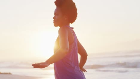 Happy-african-american-woman-practicing-yoga-on-sunny-beach