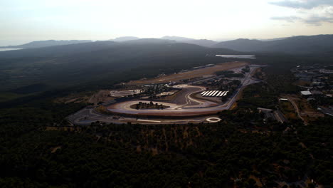 Bird's-eye-view-of-blue-striped-racing-circuit-with-countryside-backdrop.