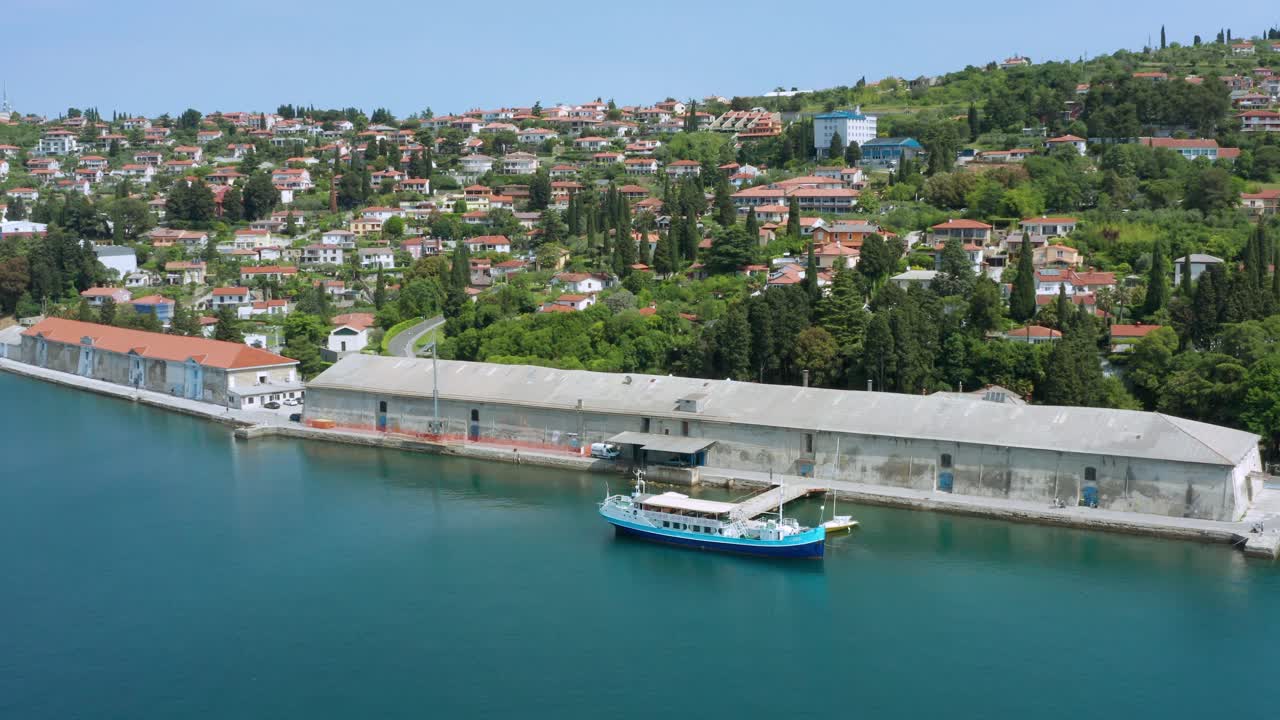 tiro aéreo lento alejándose suavemente de un muelle y un pueblo a lo largo de la riviera eslovena