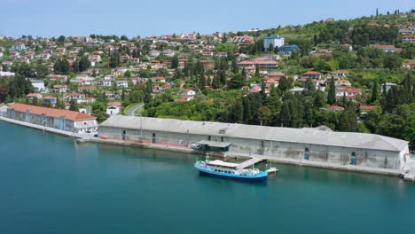 Toma-Aérea-Lenta-Alejándose-Suavemente-De-Un-Muelle-Y-Un-Pueblo-A-Lo-Largo-De-La-Riviera-Eslovena