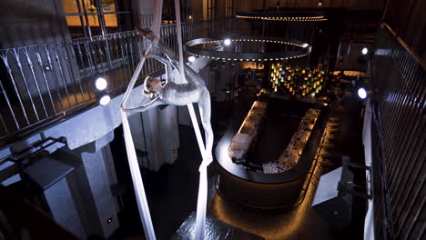 female aerialist doing a vertical split with ankle hitch on silks,club