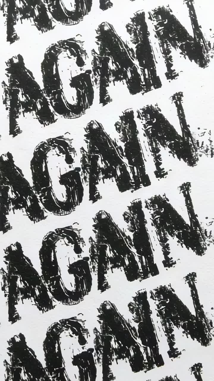 Vertical video: Hand-panning camera revealing repeated AGAIN stamps on sheet, capturing ink texture