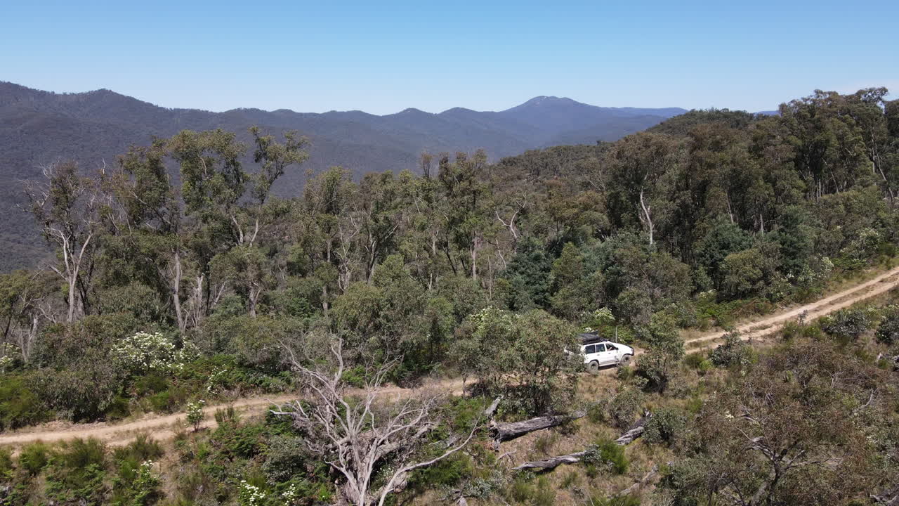 drone aéreo disparó vista lateral de 4wd conduciendo en camino de tierra hasta una montaña cerca del lago eildon, victoria australia