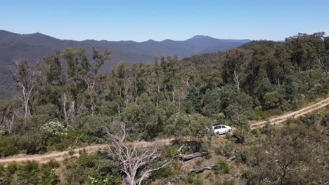 Drone-Aéreo-Disparó-Vista-Lateral-De-4wd-Conduciendo-En-Camino-De-Tierra-Hasta-Una-Montaña-Cerca-Del-Lago-Eildon,-Victoria-Australia