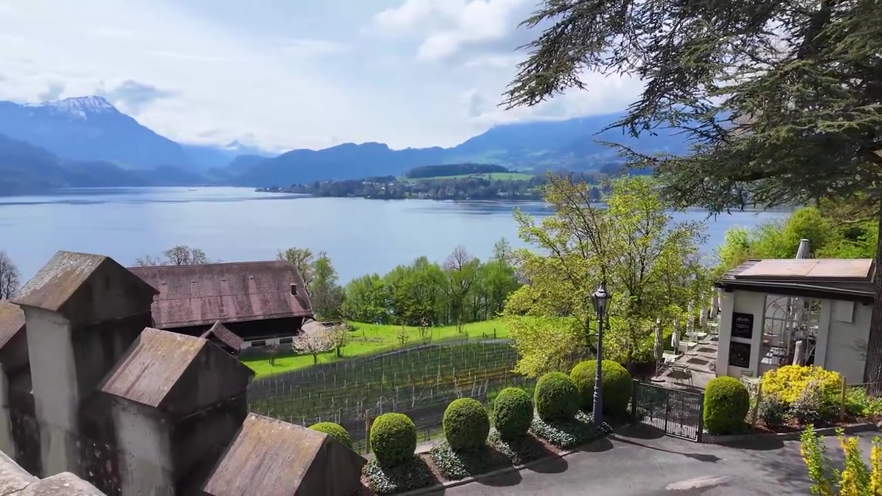 Elegant terraced gardens in Lucerne, Switzerland with sculpted hedges and stone pavilions, opening to panoramic lake and mountain views.