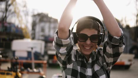 optimistic, happy girl walking on the street and listen to the good music in headphones. she is laughing and dancing. waving, gesturing with her hands