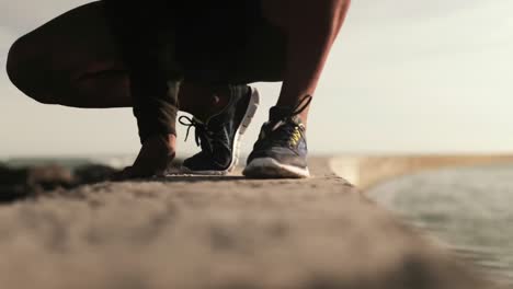 Man-tying-his-shoe-laces-while-running-on-the-promenade