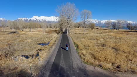 mature, senior man walking down a nature trail wearing a backpack - rear aerial view