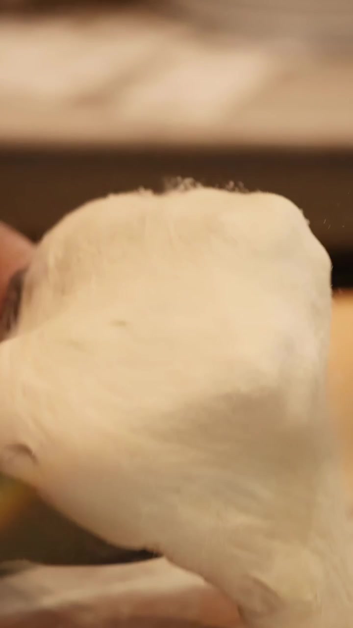 Close-up of artisan chef hands stretching and spinning fresh pizza dough in a kitchen.
