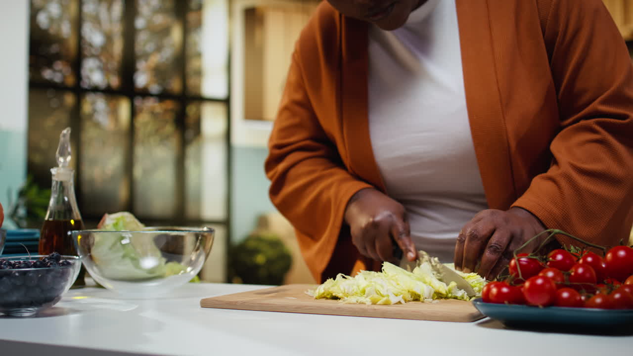 Food blogger di colore che taglia lattuga iceberg sul tagliere