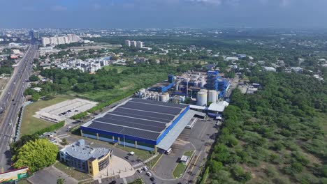 modern industrial factory with sustainable solar panels on roof. city of santiago de los caballeros on dominican republic. aerial top down shot.