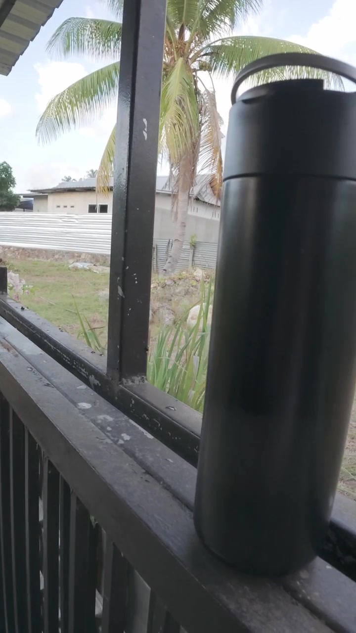 Borraccia Termica Nera Appoggiata su una Ringhiera del Balcone