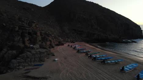 Small-boats-on-beach-in-cove-at-dusk---Side-scrolling-establishing-4k-drone-shot