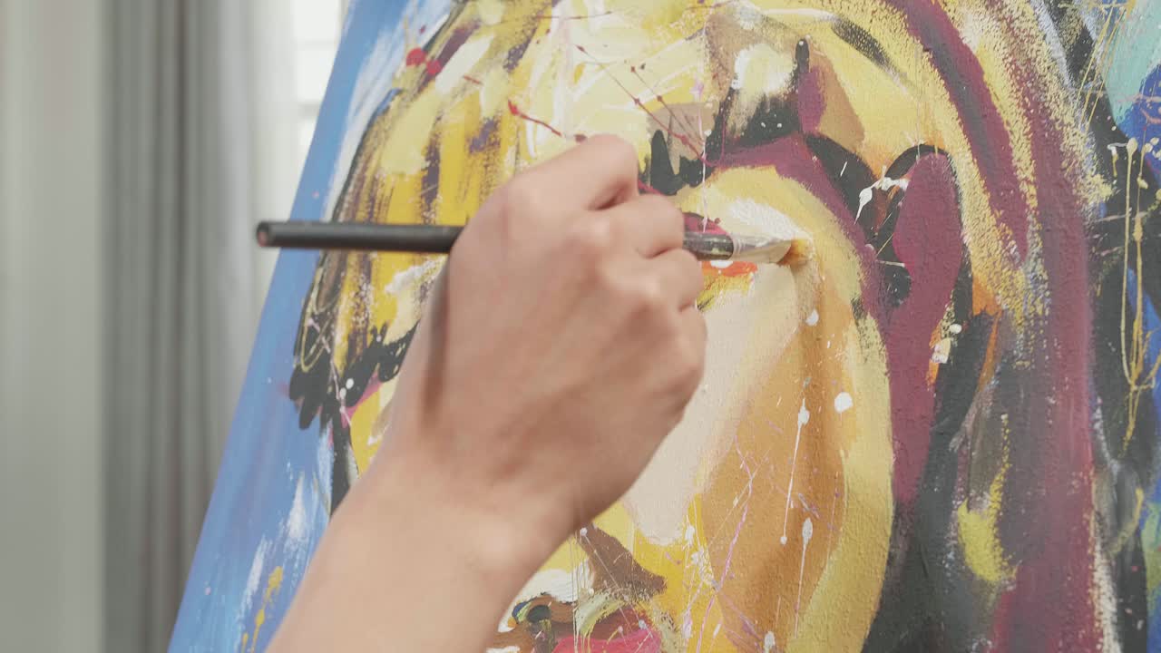 cerca de una mano sosteniendo un pincel y mezclándolo con color antes de pintar la cara de una niña en el lienzo