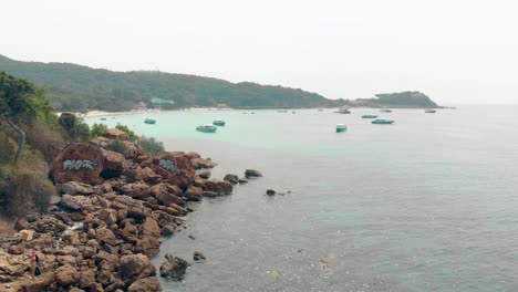 Die-Kamera-Zeigt-Strandfelsen-Mit-Touristengraffiti-Und-Meeresbucht