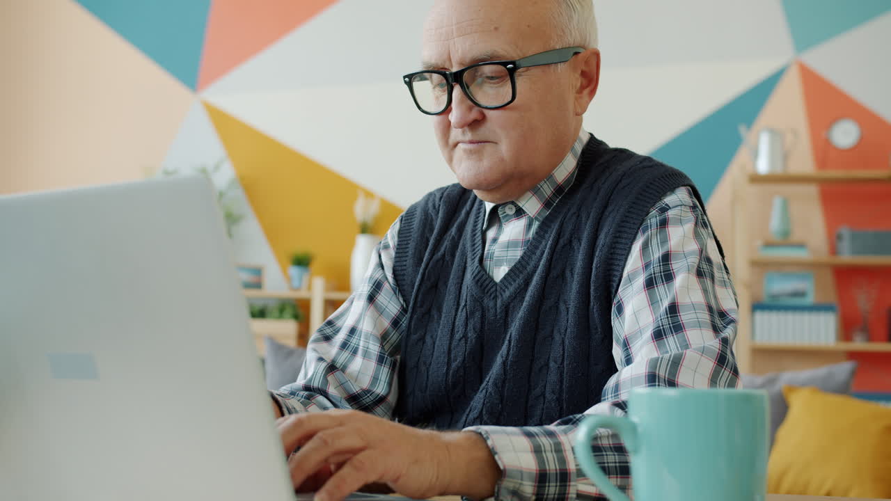 hombre mayor trabajando en una computadora portátil en casa