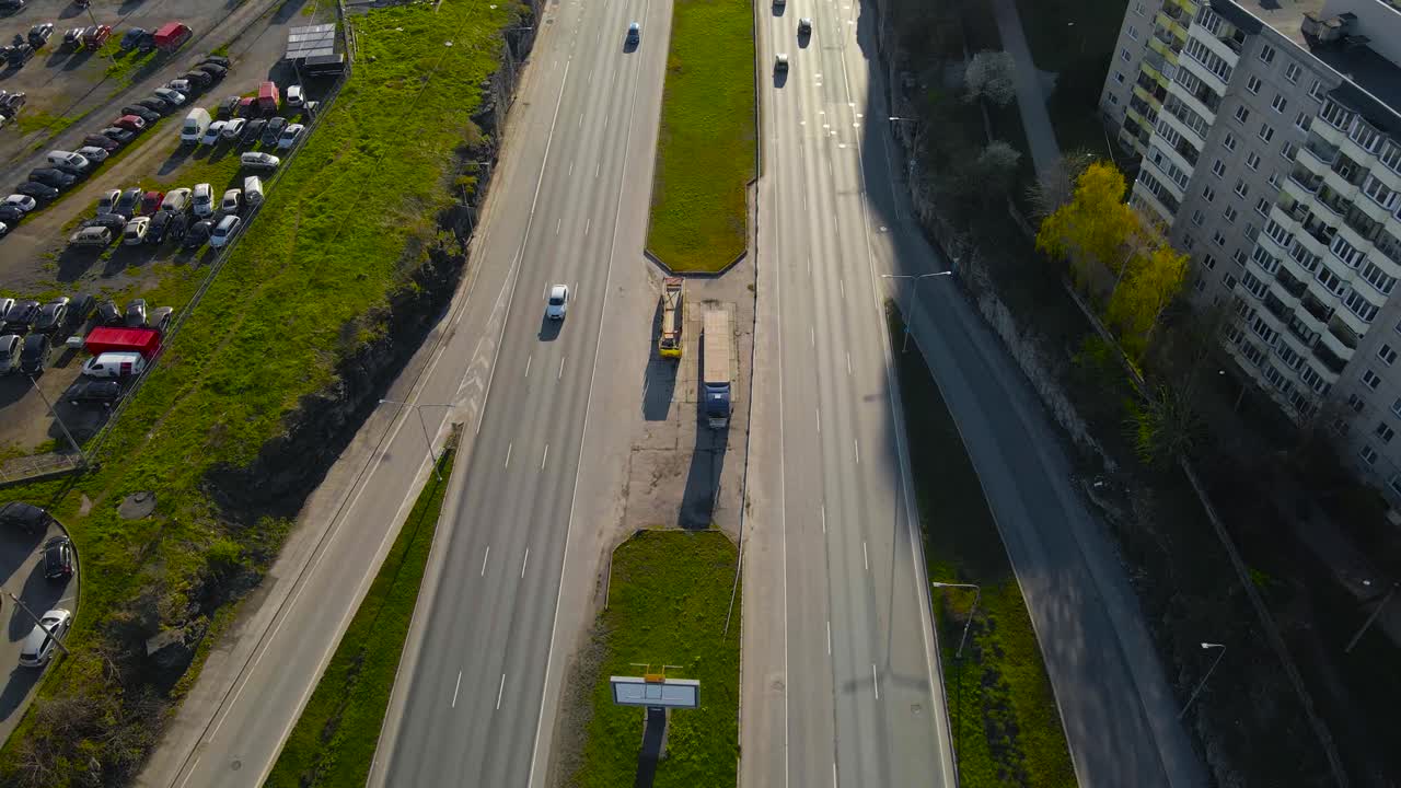 High view over multi lane highway traffic on Laagna tee, Lasnamae. Aerial moving backward above wide main road. Vibrant city district life and long road stretching into the golden hour cityscape