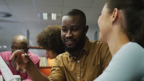 Diverse-male-and-female-business-colleagues-talking-and-holding-documents