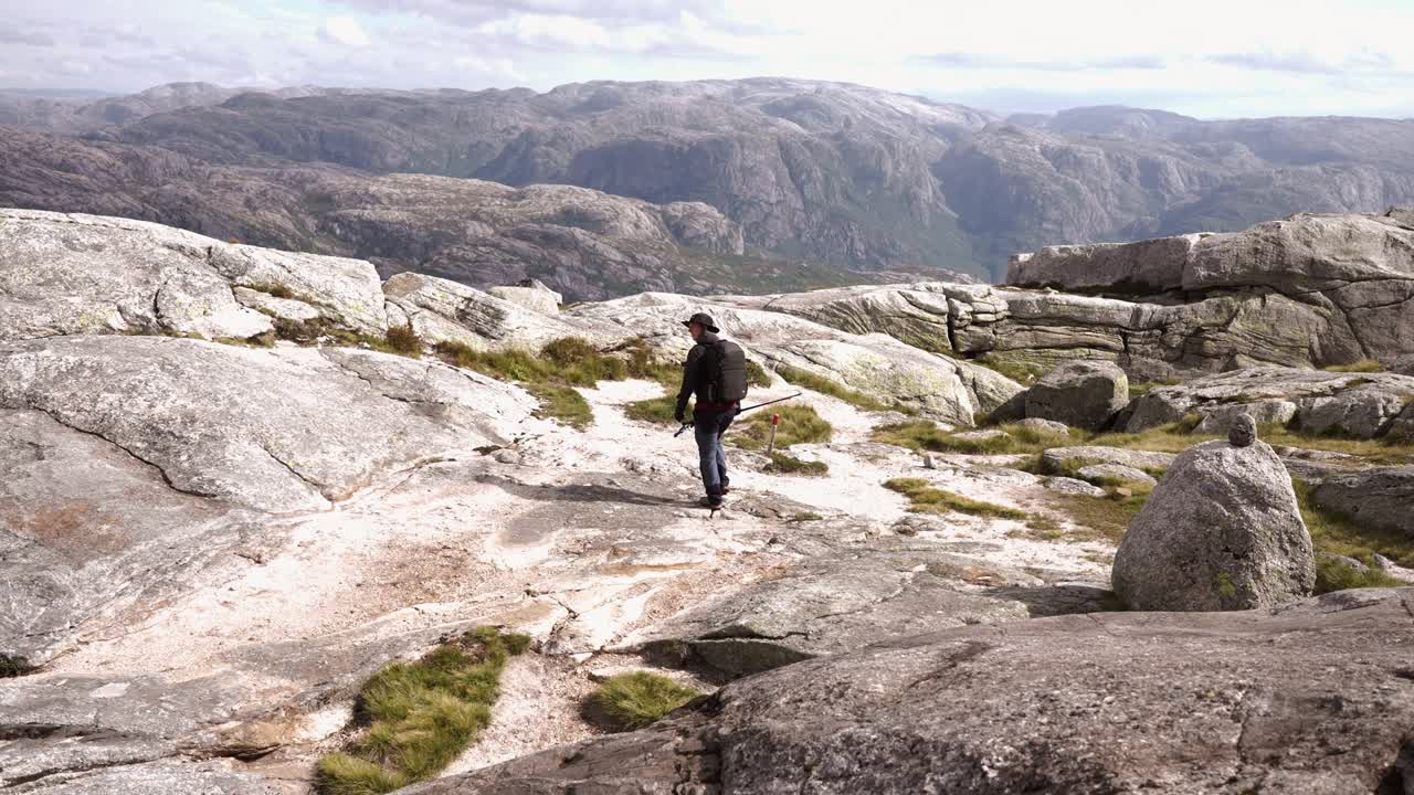 Man hiking across rocky mountain landscape in Norway under bright daylight