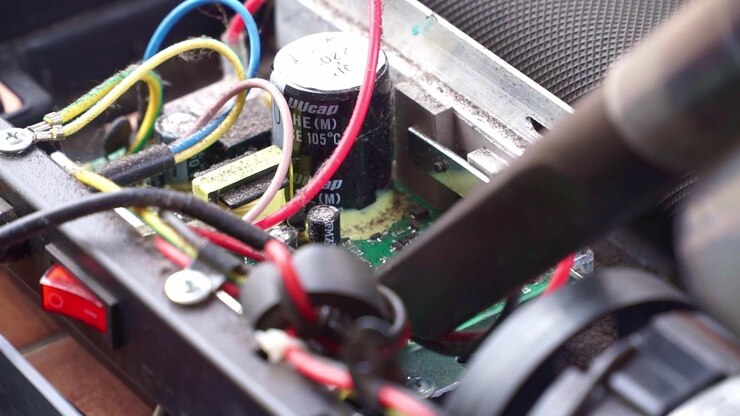 Rengøring af støvede interne maskinkomponenter med vakuumværktøj, nærbillede, reparation og vedligeholdelse af elektronik, teknisk servicescene.