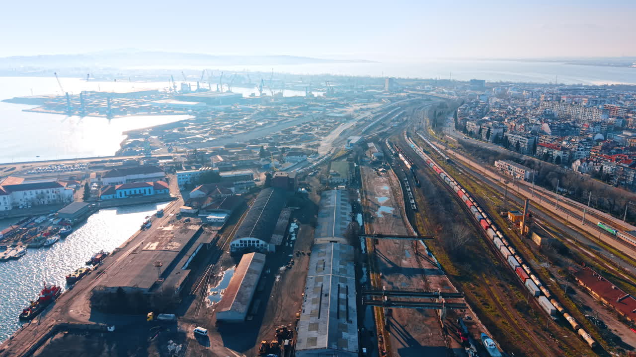 Weitläufiges Panorama einer Küstenstadt mit Industriehafen. Luftaufnahme der Stadtsilhouette, von Eisenbahngleisen und eines Seefrachtterminals.