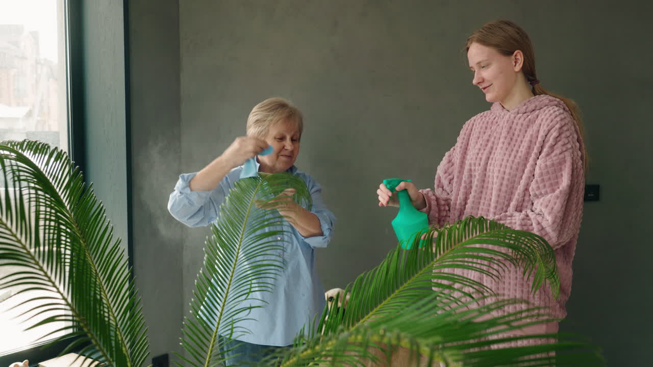 Grandmother and granddaughter watering a plant