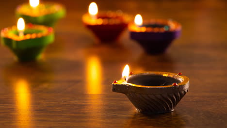 video of glowing lit diwali candles on wooden surface