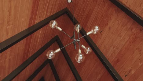 minimal ceiling light fixture hangs over patterned timber roof