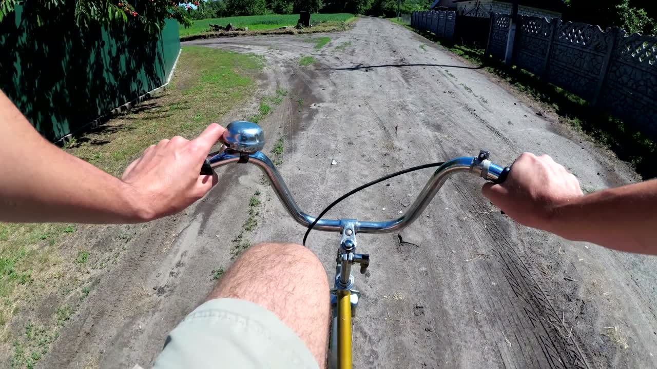한 남자가 마을의 시골 도로에서 자전거를 타고 있다. 바에 있는 가에서 볼 수 있다.