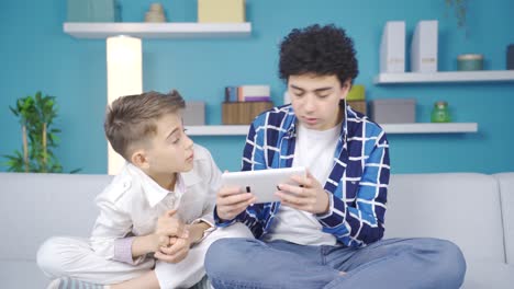 Two-brothers-are-looking-at-something-on-the-tablet-hidden-from-their-parents.