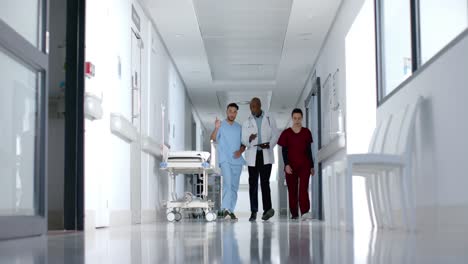 diverse doctors discussing work and walking in corridor, slow motion