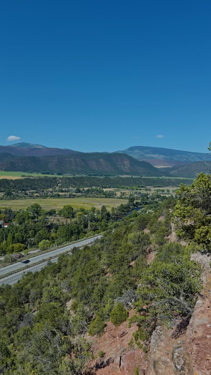 Vertical, overlooking grassy hill and rugged terrain distant mountains, Red Hill Carbondale Colorado