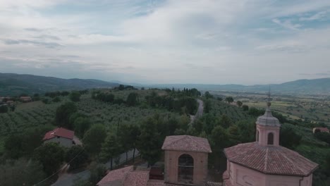 aerial drone shot pan left past church over italian countryside in umbria, italy