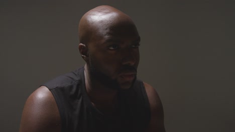 studio portrait shot of male athlete wearing sports vest against black background