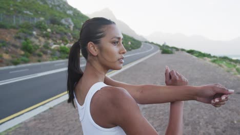 african american woman wearing sportswear performing stretching exercise on the road