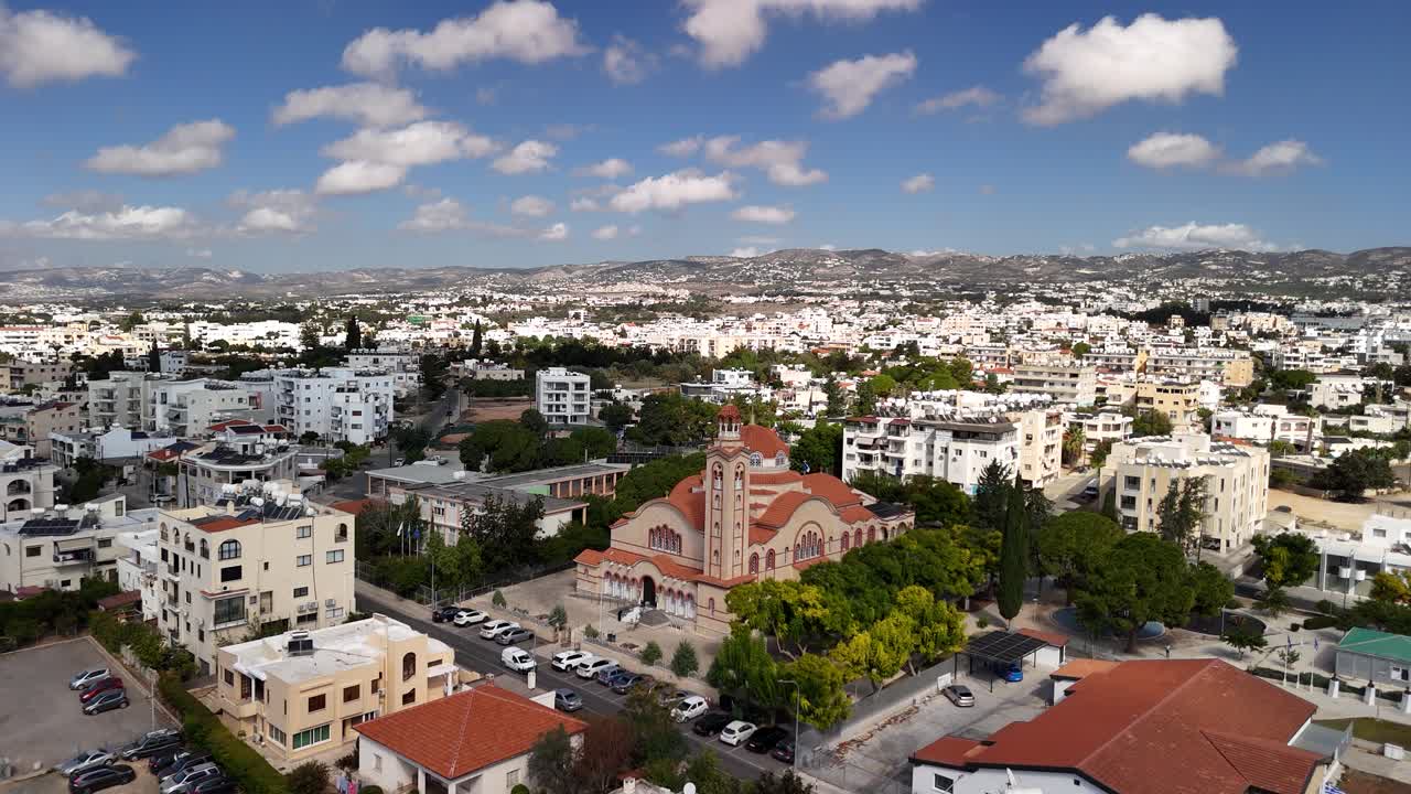 Experience an aerial perspective of a lively city bustling with activity. The clear, blue sky highlights the beautiful buildings and landscape as afternoon light brings a warm glow to the urban area