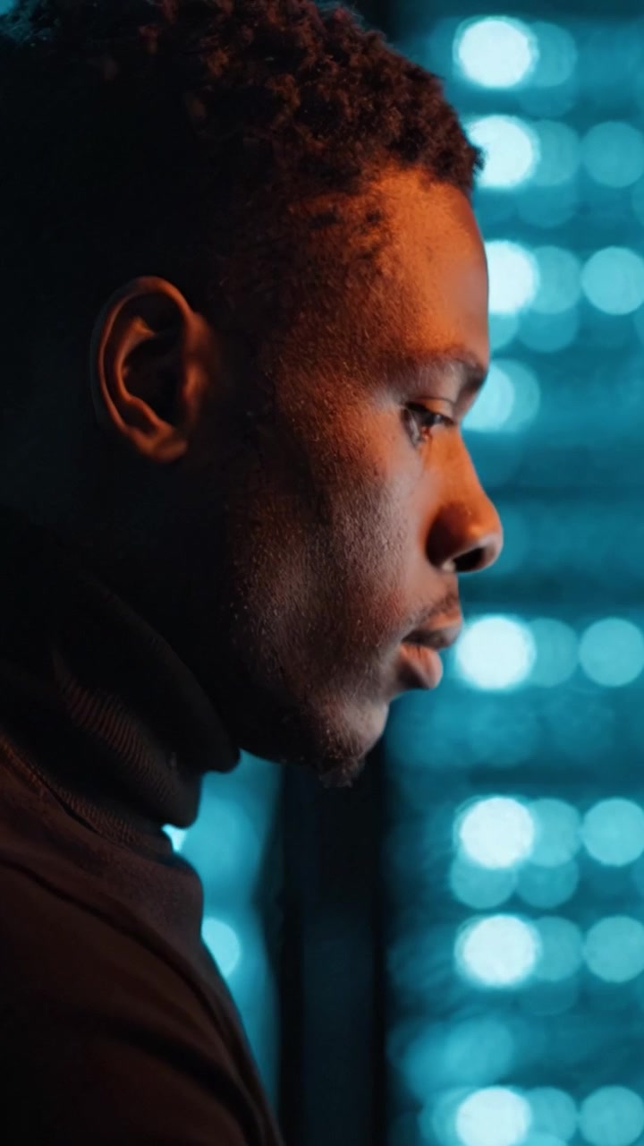 A contemplative profile of a man against a vibrant blue background, illuminating inner thoughts and self-reflection in an intimate cinematic moment.