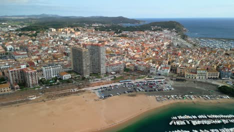 sant antoni de calonge, a charming coastal town on the costa brava in spain, reveals its beauty from an aerial perspective, showcasing the beach, colorful buildings, and boats moored in the harbor