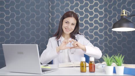 mujer doctora haciendo corazón mirando a la cámara.
