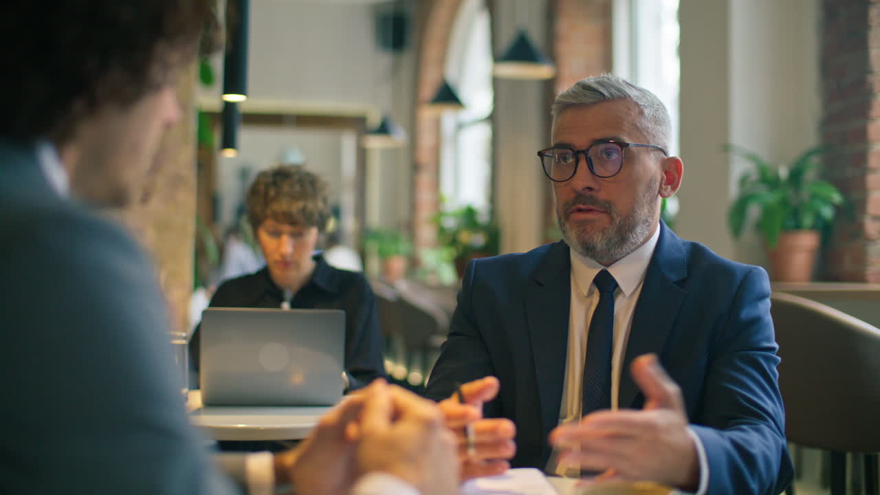 Senior Executive Having Business Discussion with Colleague at Cafe