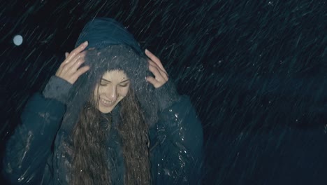 woman-with-dark-hair-in-jacket-jumps-for-joy-in-heavy-rain